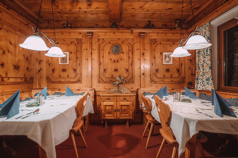 Gemütliches Hotel Austria Restaurant mit Holzwänden und Tischen, das für das Abendessen mit blauen Servietten und weißer Tischwäsche vorbereitet ist