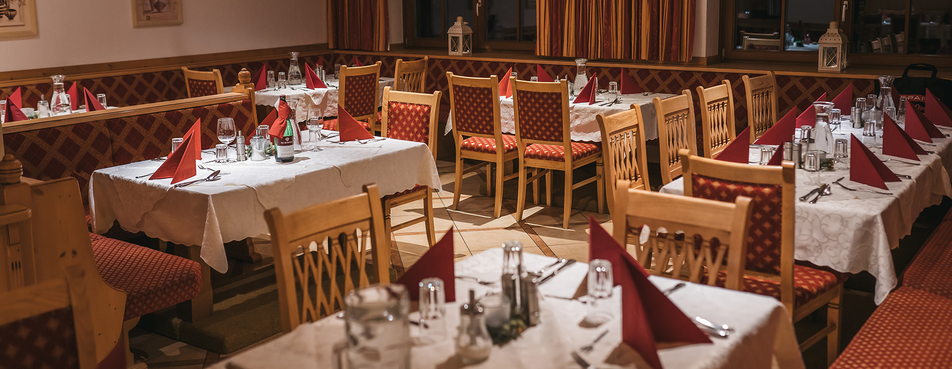 Das Hotel Austria Restaurant mit traditioneller Tischdekoration, roten Akzenten und gemütlichem Ambiente, wartet auf die Ankunft der Gäste